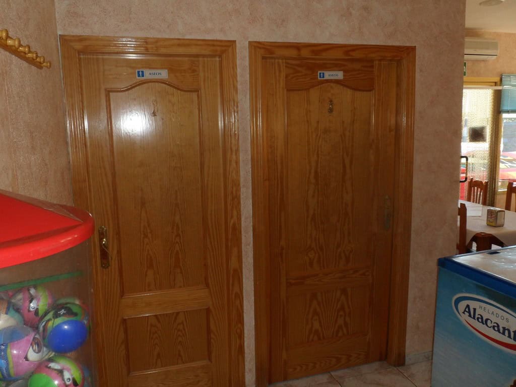 Commercial property doors in Cuevas del Campo, Granada, with wooden finishes and signage.