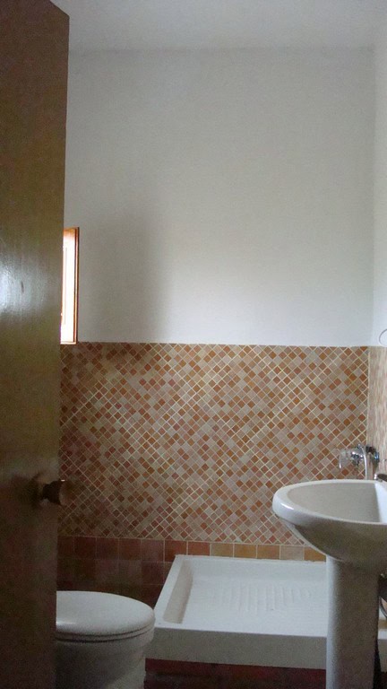 Bright bathroom in rural Hijate property, featuring a tiled wall, white fixtures, and natural light.