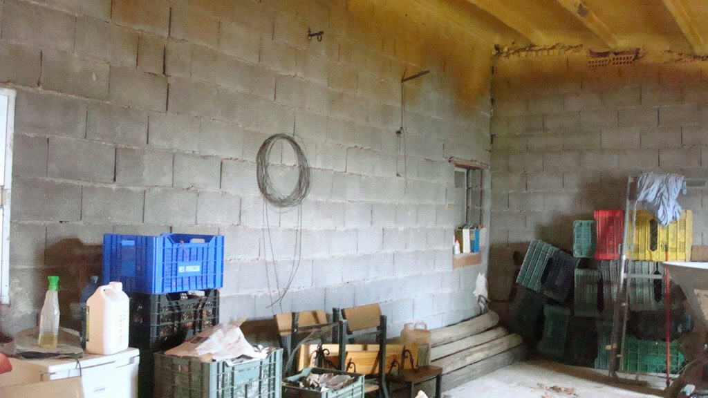 Interior view of a rustic rural property in Hijate, Almeria, showing unfinished walls and storage cr.