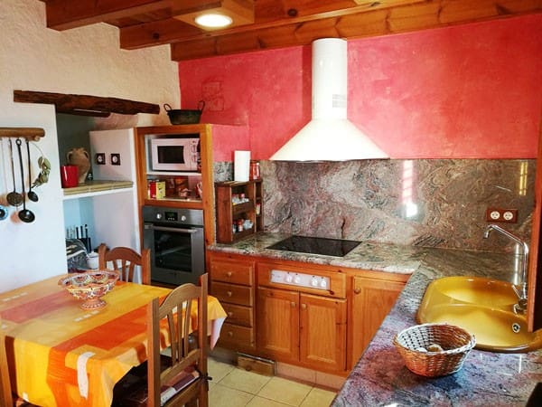 Charming cave house kitchen with rustic wooden cabinets, modern appliances, and vibrant red walls in.