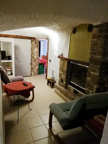 Charming cave house living room with rustic stone walls and modern furnishings in Galera, Granada.