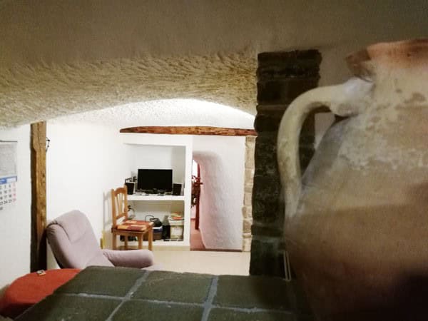 Cozy interior of a cave house with rustic decor in Galera, Granada, featuring a living area with a T.