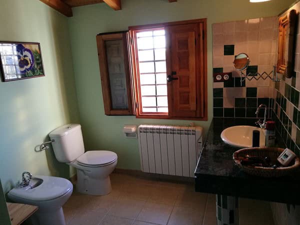 Charming cave house bathroom with traditional tiles, wooden window, and rustic decor in Galera, Gran.
