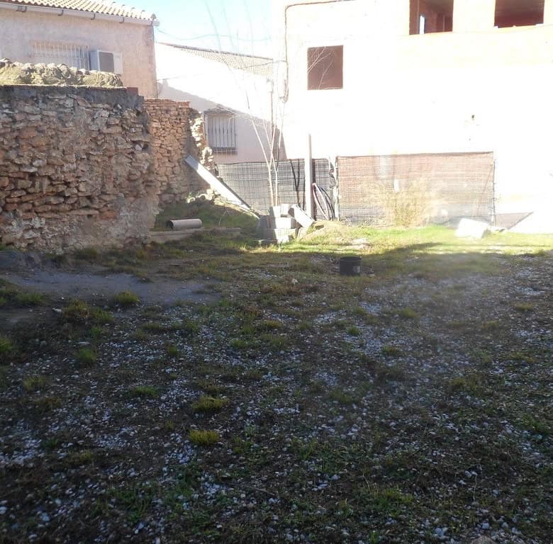 Cave house in Cuevas del Campo, Granada, with an open yard and surrounding stone walls.
