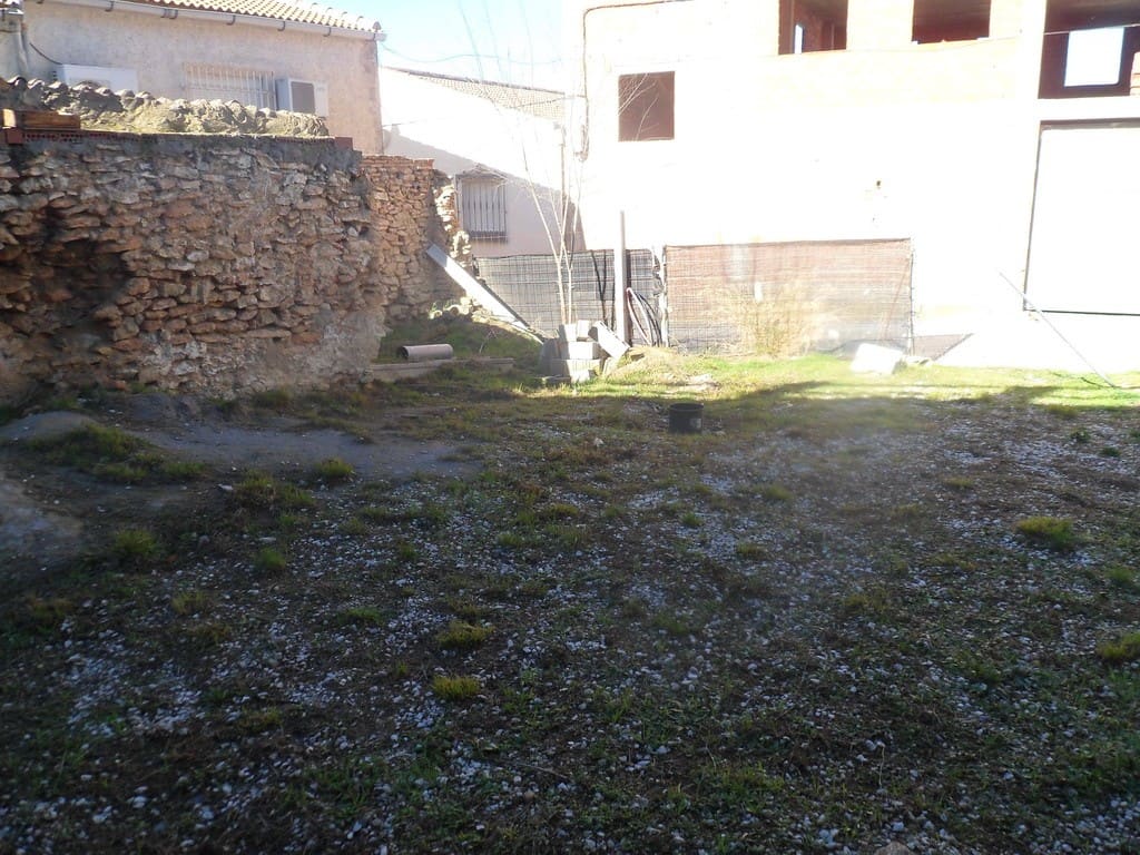 Cave house in Cuevas del Campo, Granada, with an open yard and surrounding stone walls.