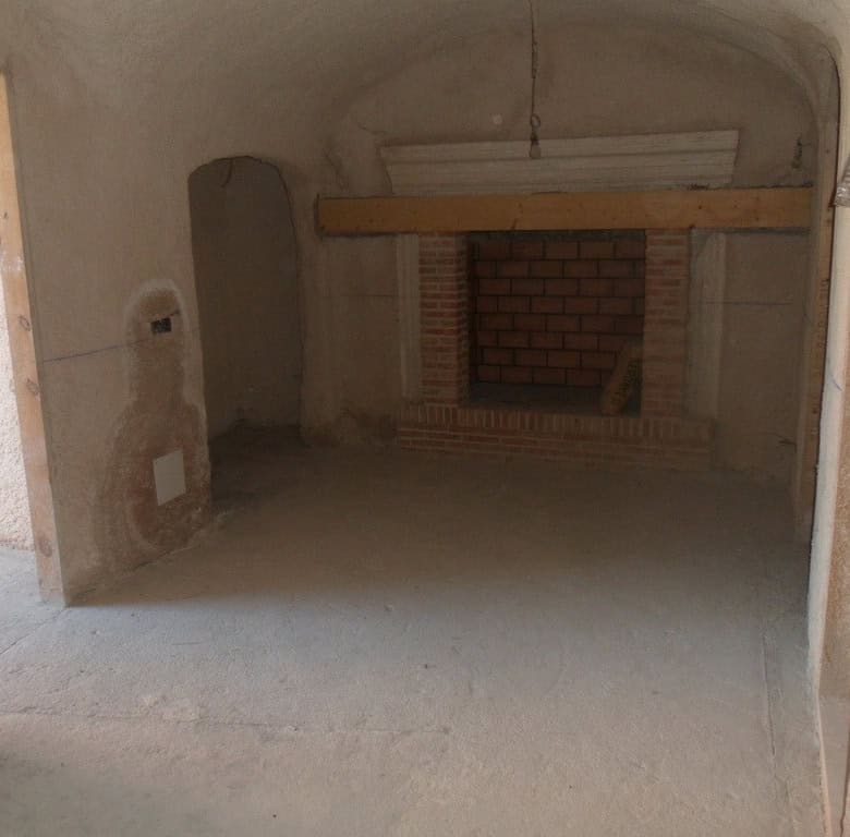 Cave house interior under renovation in Cuevas del Campo, Granada, with brick fireplace and rustic c.