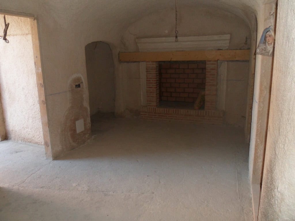 Cave house interior under renovation in Cuevas del Campo, Granada, with brick fireplace and rustic c.