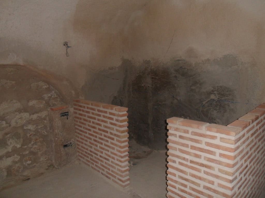 Cave house interior with brick walls and rustic stone features in Cuevas del Campo, Granada.