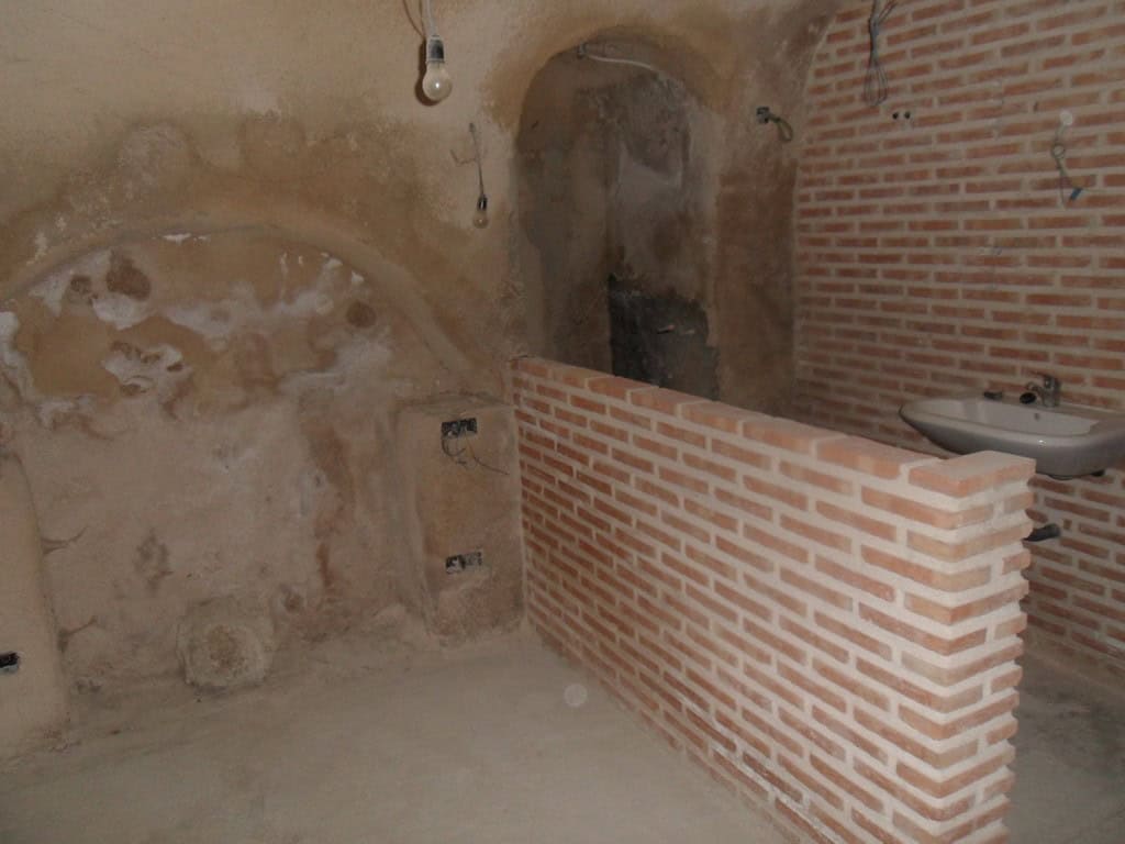 Cave house interior with brick partition and rustic walls in Cuevas del Campo, Granada.