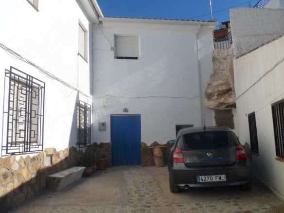 Cave house with white exterior walls and blue door in Freila, Granada, Spain.