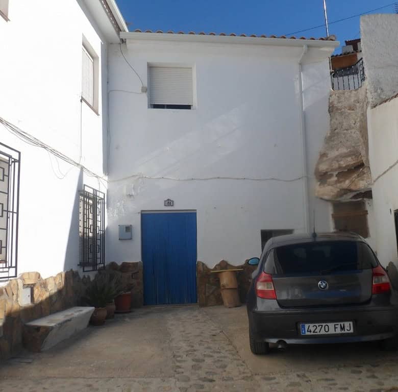 Cave house with white exterior walls and blue door in Freila, Granada, Spain.