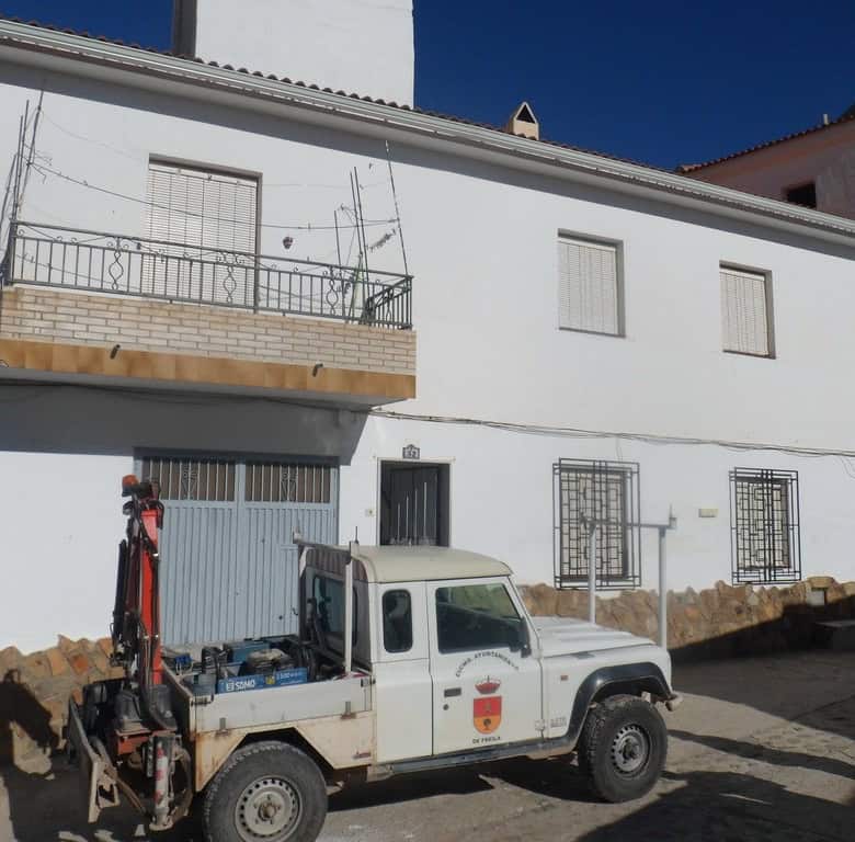 Cave house in Freila, Granada, with a white exterior and a small balcony, set against a clear blue s.