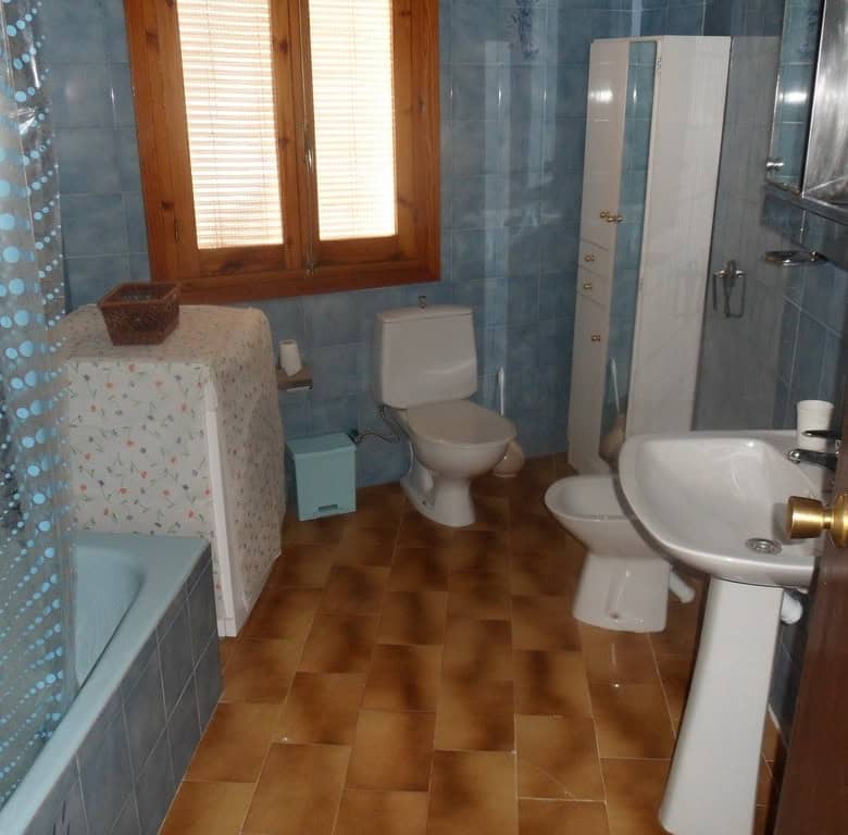 Charming cave house interior in Freila, Granada, featuring a bathroom with a toilet, sink, and showe.