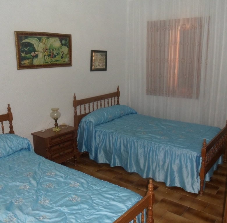 Cave House interior with two beds, wooden furniture, and decorative wall art in Freila, Granada.