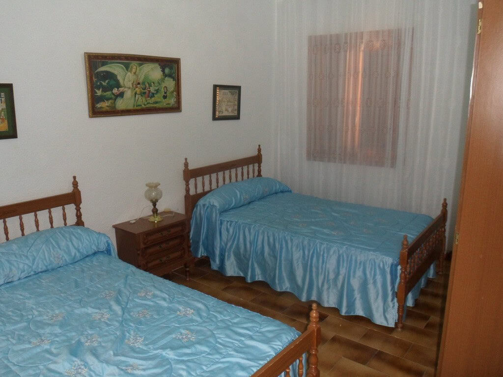 Cave House interior with two beds, wooden furniture, and decorative wall art in Freila, Granada.