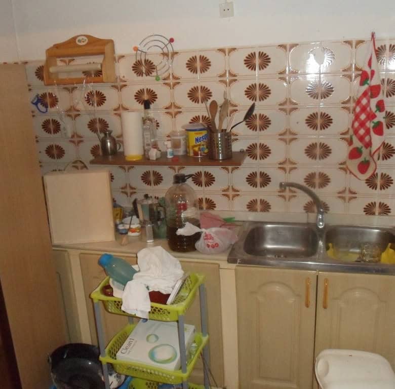 Cave house interior in Freila, Granada, featuring a small kitchen with tiled walls and basic applian.