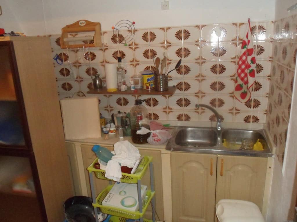 Cave house interior in Freila, Granada, featuring a small kitchen with tiled walls and basic applian.