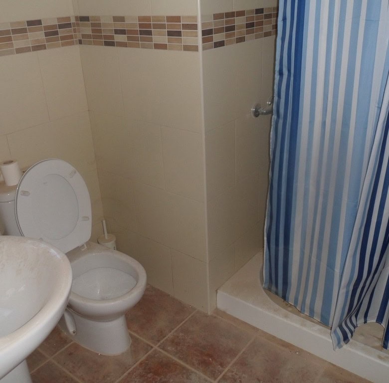 Cozy bathroom with toilet and shower in a traditional cave house in Freila, Granada.