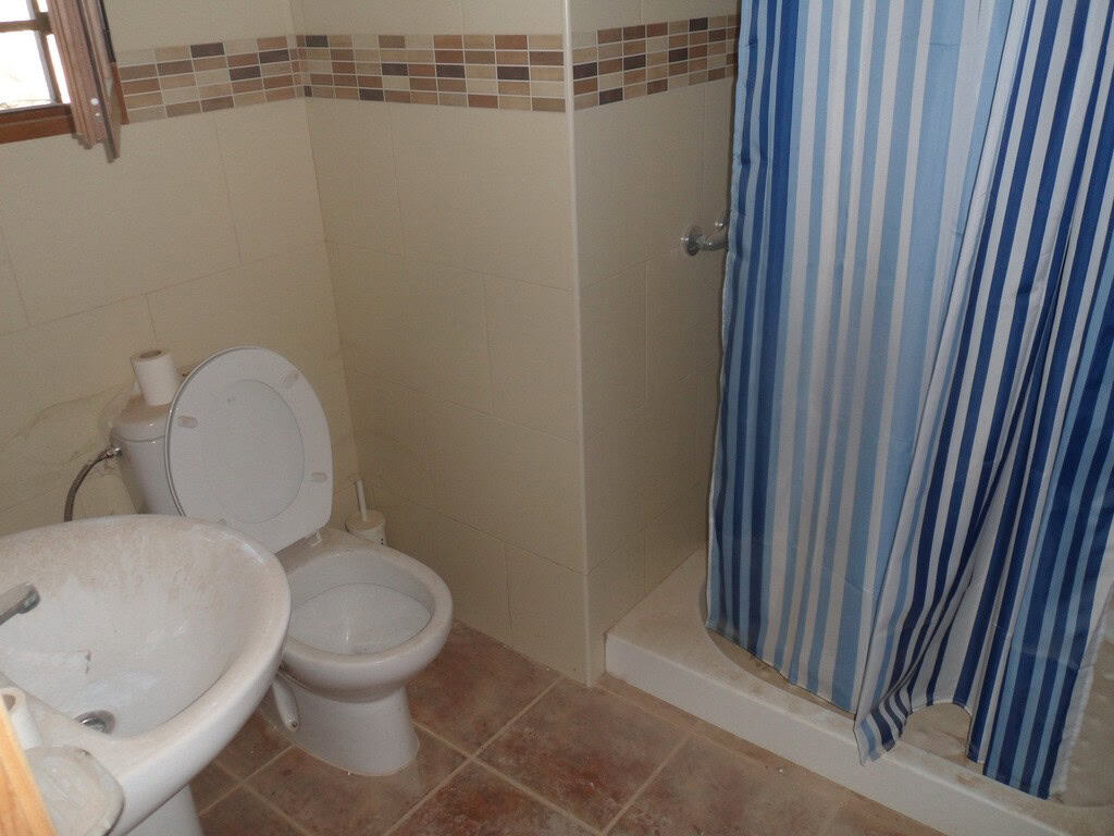 Cozy bathroom with toilet and shower in a traditional cave house in Freila, Granada.