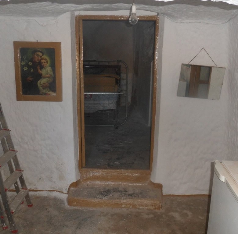 Cave house interior in Freila, Granada with rustic white walls and simple furnishings.