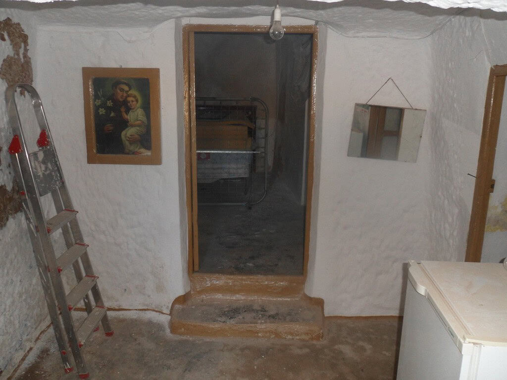Cave house interior in Freila, Granada with rustic white walls and simple furnishings.