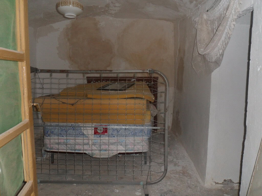 Unique cave house interior in Freila, Granada, with rustic walls and simple furnishings.