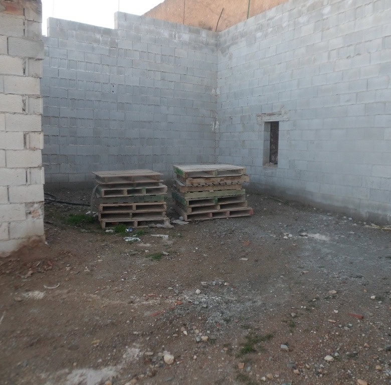 Cave house construction site in Freila, Granada, with unfinished stone walls and building materials.