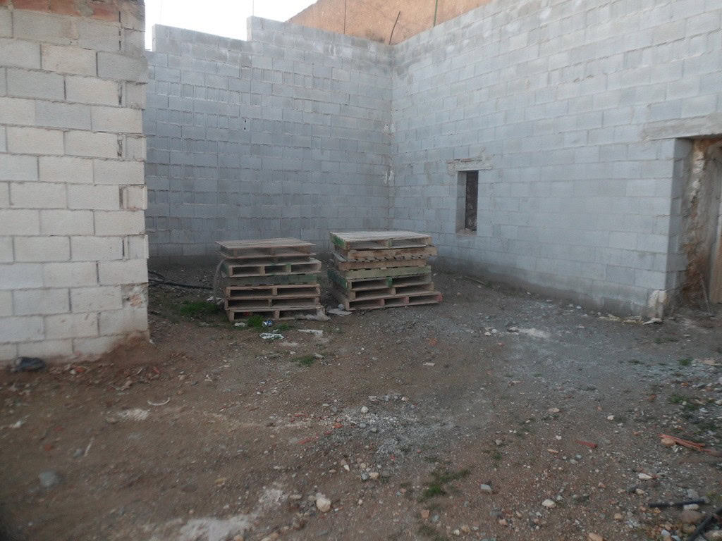 Cave house construction site in Freila, Granada, with unfinished stone walls and building materials.
