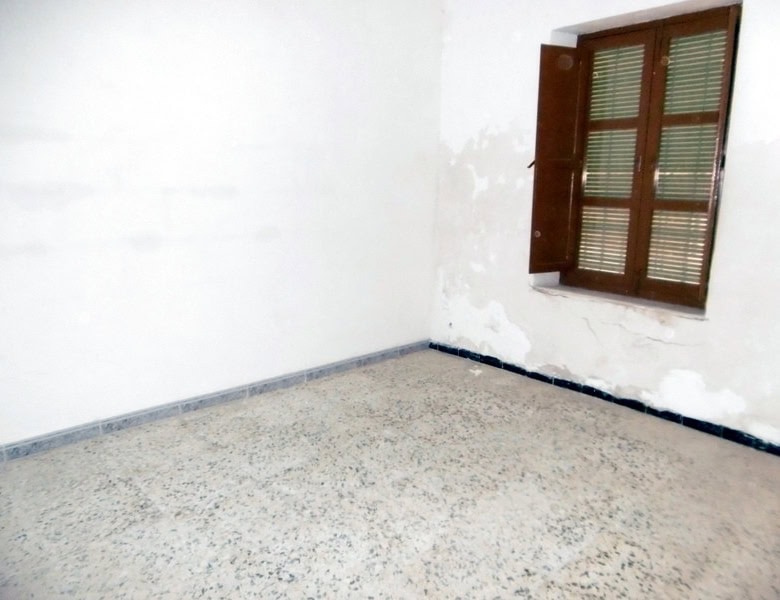 Interior view of a vacant room in a town house in Tijola, Almeria, with a window and white walls.