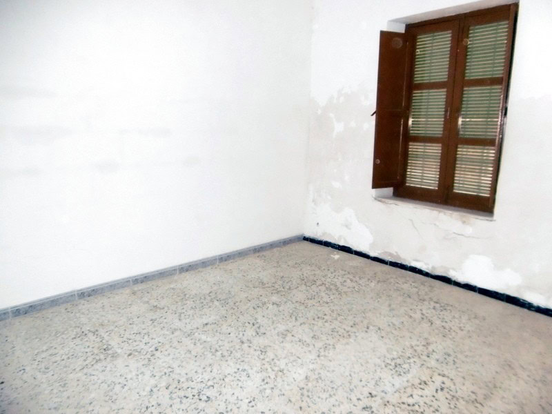 Interior view of a vacant room in a town house in Tijola, Almeria, with a window and white walls.