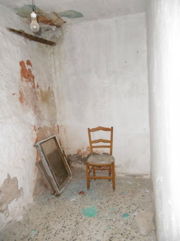 Charming interior of a town house in Tijola, Almeria, showing an unfinished room with a wooden chair.