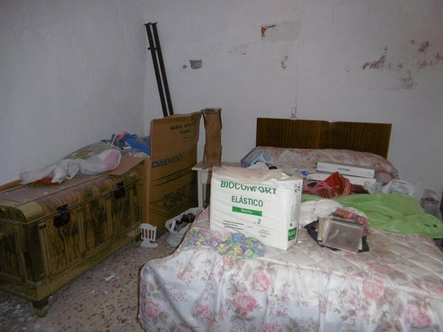 Charming town house interior in Tijola, Almeria, showing a bedroom with old furniture and cluttered.