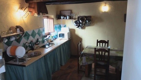 Interior view of a traditional kitchen in Quesada, Jaen, featuring wooden furniture and basic applia.