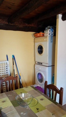 Laundry area with stacked washing machine and drying rack in Quesada town house.