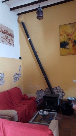 Interior view of a town house living room with a wood stove and colorful wall art in Quesada, Jaen.