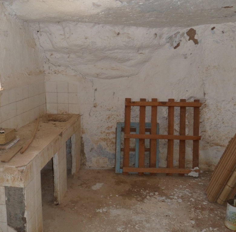 Cave house interior with rustic stone walls and simple furnishings in Freila, Granada. Ideal for uni.