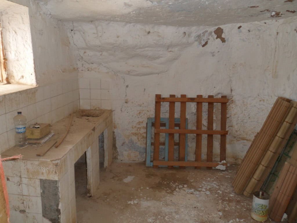 Cave house interior with rustic stone walls and simple furnishings in Freila, Granada. Ideal for uni.