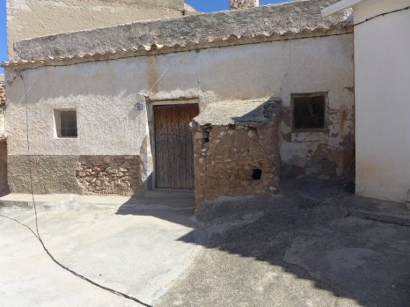 Cave house in Freila, Granada, with rustic stone walls and wooden door.