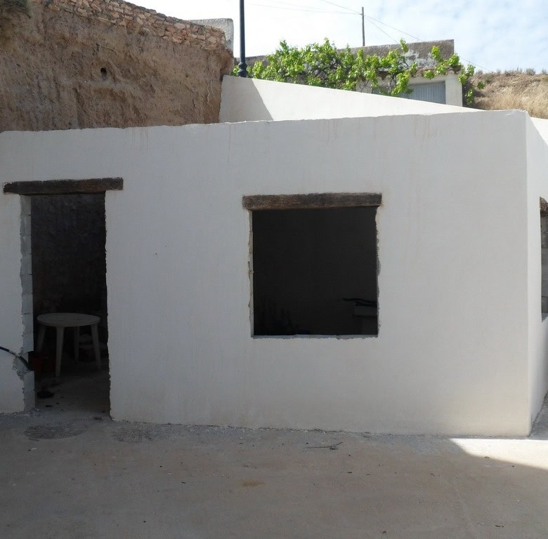 Cave house exterior in Freila, Granada, with whitewashed walls and rustic openings.