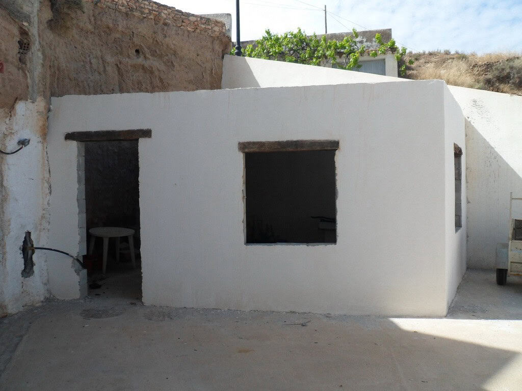 Cave house exterior in Freila, Granada, with whitewashed walls and rustic openings.