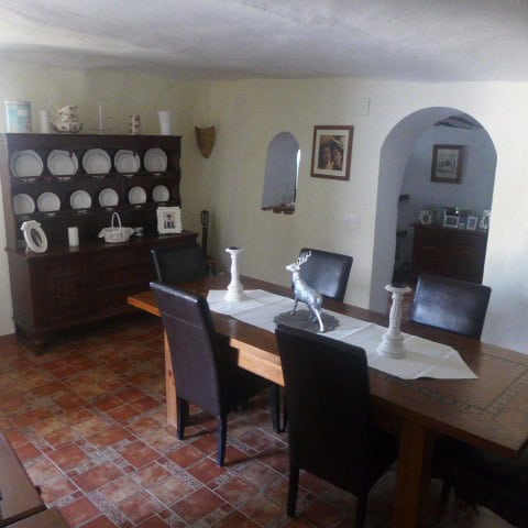 Cave house interior in Galera, Granada, featuring a dining area with a wooden table, black chairs, a.