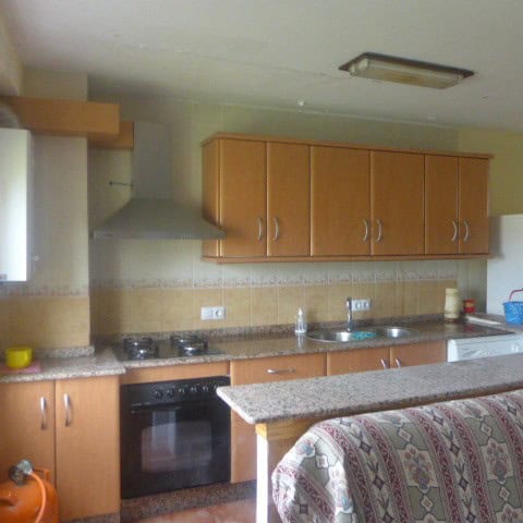 Kitchen interior of a town house in Castril, Granada, featuring wooden cabinets and modern appliance.