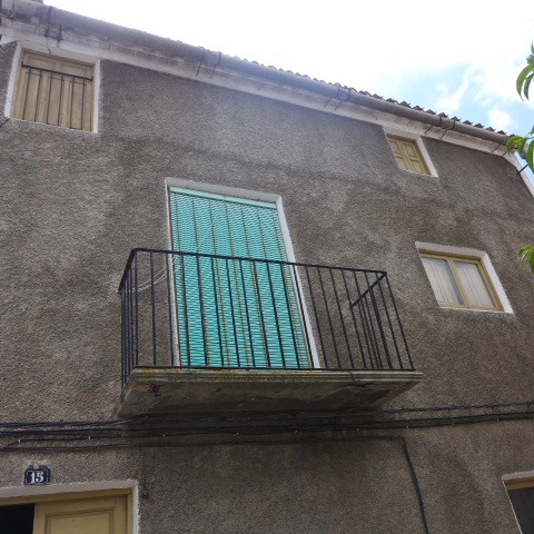 Balcony of a town house in Castril, Granada, with a blue shutter and small windows.
