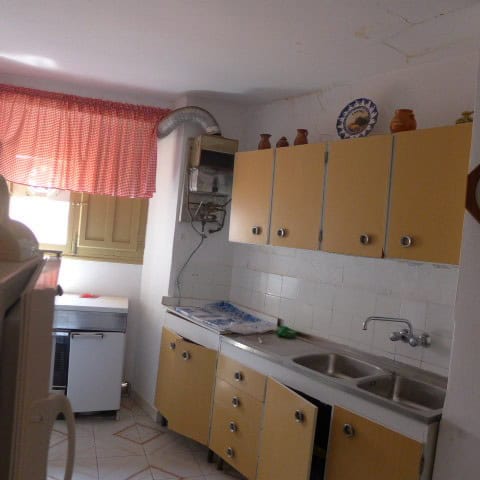 Charming kitchen in a town house in Castril, Granada, featuring yellow cabinets, a double sink, and.