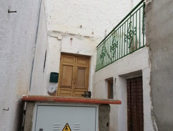 Town house exterior in Cullar, Granada with rustic wooden door and narrow alleyway.