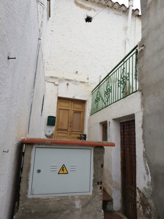 Town house exterior in Cullar, Granada with rustic wooden door and narrow alleyway.
