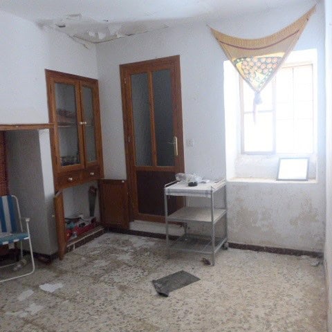 Interior of a town house in Cullar, Granada, showing a simple, slightly worn living space with a win.