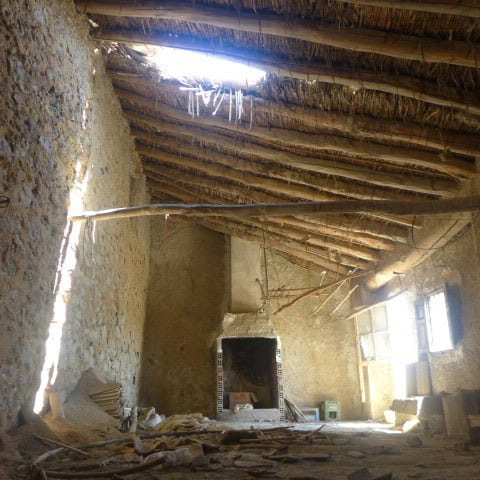 Interior of a rustic town house in Cullar, Granada with exposed wooden beams and stone walls.