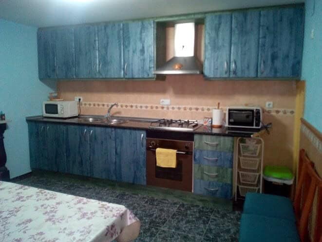 Kitchen with blue cabinets and essential appliances in Tijola village property.