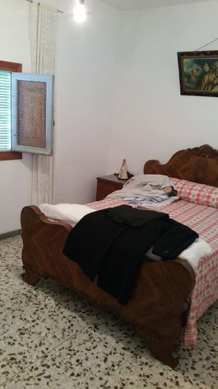Cozy bedroom in a village property in Purchena, Almeria, featuring a wooden bed, window with shutter.